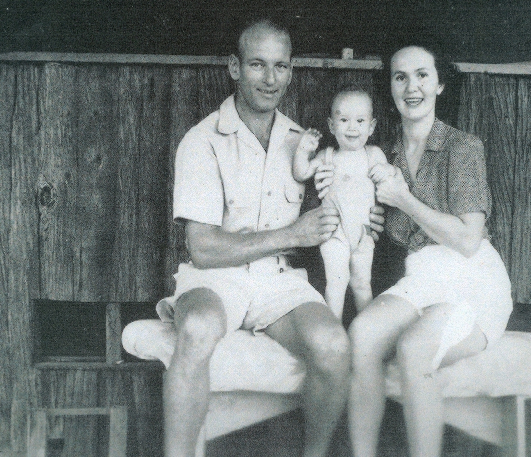 Mother, Father and Baby sitting outside a house.